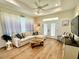 Well-lit living room showcases plank flooring, and a comfortable sectional with bright windows at 12077 Lakeshore Way, Oxford, FL 34484