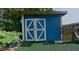 A blue outdoor shed with decorative white doors complements the green lawn, offering stylish storage for outdoor tools and supplies at 1224 Lakeview Dr, Clermont, FL 34711