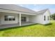 Backyard view featuring a covered patio with sliding glass doors, complemented by lush green grass at 12565 Cynthia Ln, Clermont, FL 34715