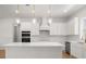 Modern white kitchen featuring stainless steel appliances, pendant lights, and a large island at 12565 Cynthia Ln, Clermont, FL 34715