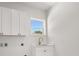 Bright laundry room with white cabinets and a sink, offering both functionality and style at 12565 Cynthia Ln, Clermont, FL 34715