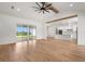 Bright living room featuring wood floors, modern ceiling fan, and kitchen and patio views at 12565 Cynthia Ln, Clermont, FL 34715