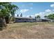 Lush backyard with a gray home in the background, surrounded by mature trees and fencing at 1406 Hope Ct, Tavares, FL 32778