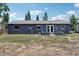 Wide view of backyard featuring a gray home with a metal roof, ladder, and minimalist landscaping at 1406 Hope Ct, Tavares, FL 32778