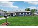Charming home showcasing a well-maintained front lawn, gray exterior, and metal roof at 1406 Hope Ct, Tavares, FL 32778