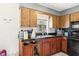 Features wood cabinets, black appliances, and a black countertop, with a window for natural light at 1406 Hope Ct, Tavares, FL 32778