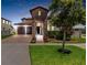 Beautiful home exterior with stone accents, a well-manicured lawn, and a brick driveway leading to a two-car garage at 14907 Guava Bay Dr, Winter Garden, FL 34787