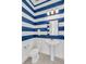 Stylish half-bath with blue and white striped walls and pedestal sink at 14907 Guava Bay Dr, Winter Garden, FL 34787