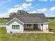 Aerial view of a white farmhouse with a metal roof, covered porch, and barbecue on the patio at 1560 Ne 17Th St, Sumterville, FL 33585