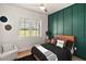 Modern bedroom showcasing green accent wall, bed with nightstand, side chair, and a window with blind at 1560 Ne 17Th St, Sumterville, FL 33585