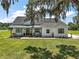 Beautiful white farmhouse with a metal roof, covered porch, and lush front lawn at 1560 Ne 17Th St, Sumterville, FL 33585