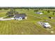 Aerial view shows home, outbuildings, and a garden in a large yard with tire tracks in the manicured lawn at 1560 Ne 17Th St, Sumterville, FL 33585