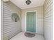 Inviting front entryway with a decorative tree accent, a green door and a neutral color scheme at 1713 Jadestone Ter, The Villages, FL 32162