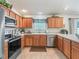 Functional kitchen featuring wooden cabinetry, stainless steel appliances, and ample countertop space at 1713 Jadestone Ter, The Villages, FL 32162