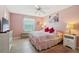 Cozy pink bedroom featuring a ceiling fan, a large window, and a comfortable bed at 1728 Morelos Rd, The Villages, FL 32159