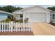 Inviting front exterior featuring a cozy porch with a white picket fence and colorful flowerbeds at 1728 Morelos Rd, The Villages, FL 32159