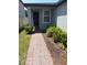 Beautiful front entrance with a brick pathway, manicured shrubs, and a freshly painted door at 1808 Carnostie Rd, Winter Haven, FL 33884