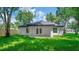 Backyard view featuring a covered patio with double doors, lush green grass, and mature trees creating a serene outdoor space at 201 Hillside Ave, Umatilla, FL 32784