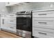 Modern kitchen features white cabinets, matte black hardware, stone countertops, mosaic tile backsplash, and stainless steel range at 201 Hillside Ave, Umatilla, FL 32784