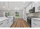 Well-lit kitchen with stainless steel appliances, island, wood flooring, white cabinetry, and backyard view at 201 Hillside Ave, Umatilla, FL 32784