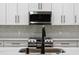 Close-up of kitchen with stainless steel appliances, white cabinets, quartz countertop, and stylish backsplash at 201 Hillside Ave, Umatilla, FL 32784