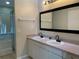 Bright bathroom featuring double sinks, framed mirror, and a glass enclosed shower and tub at 206 Orchid Dr, Davenport, FL 33897