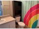 Bathroom featuring toilet with overhead shelving, neutral countertop and colorful shower curtain at 206 Orchid Dr, Davenport, FL 33897