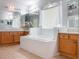 Bathroom featuring a tub, white tile, and light wood cabinets and large mirrors at 25243 River Crest Dr, Leesburg, FL 34748