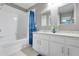 Well-lit bathroom with a bathtub, shower, and a vanity featuring a granite countertop and dual mirrors at 2530 Maneshaw Ln, Kissimmee, FL 34747