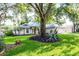 Attractive home with an expansive lawn and mature landscaping, featuring tropical plantings and a charming, columned front entrance at 2711 Bayview Dr, Eustis, FL 32726