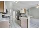 Well-lit kitchen with white tile flooring, stainless steel appliances, and access to other rooms at 2711 Bayview Dr, Eustis, FL 32726