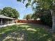 View of the grassy backyard, featuring a privacy fence, mature trees, and an enclosed porch at 2850 Aragon Ter, Lake Mary, FL 32746