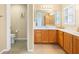 Bright bathroom with wood cabinets, dual sinks, white countertops, tiled floors, toilet and separate shower at 3008 Bridgefield Ct, The Villages, FL 32162