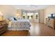 Primary bedroom with wood floors, bay window with valance, ceiling fan, and dresser with television at 3008 Bridgefield Ct, The Villages, FL 32162
