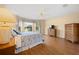 Bedroom with wood floors, large bay window with valance, ceiling fan, and dresser with television at 3008 Bridgefield Ct, The Villages, FL 32162