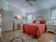 Bedroom featuring a red bedspread, white furniture, and hardwood floors, lit by bedside lamps at 3112 Burbank Ln, The Villages, FL 32162
