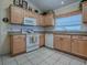 Cozy kitchen featuring wood cabinets, white appliances, granite countertops, and tile flooring at 3112 Burbank Ln, The Villages, FL 32162