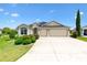 Inviting front exterior featuring a two-car garage, manicured landscaping, and neutral color palette at 3405 Nursery Pl, The Villages, FL 32163