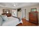 Spacious bedroom with a trey ceiling, ceiling fan, wood floors, and two dressers; doorway leads to ensuite bathroom at 3411 Eisenhower Way, The Villages, FL 32163