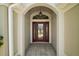 The front entrance features a beautiful glass door framed by an arched entryway, offering a welcoming glimpse inside at 3411 Eisenhower Way, The Villages, FL 32163