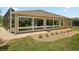 Rear exterior view of home featuring sunroom, brick patio, well-manicured lawn, and landscaping at 3411 Eisenhower Way, The Villages, FL 32163
