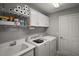 Functional laundry room with a washer, dryer, sink, and overhead storage cabinets at 3411 Eisenhower Way, The Villages, FL 32163