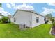 Well-maintained backyard featuring a white exterior, lush green lawn, and a modern air conditioning unit at 412 Hildalgo Dr, The Villages, FL 32159