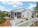 Charming home featuring a screened porch and a well-maintained yard with decorative white picket fence at 412 Hildalgo Dr, The Villages, FL 32159