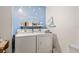Well-lit laundry room with washer, dryer, shelving and whimsical wall art at 412 Hildalgo Dr, The Villages, FL 32159
