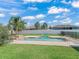 Beautiful pool area with a custom stone water feature, grassy lawn, and two Adirondack chairs under a partly cloudy sky at 4730 Se 31St St, Ocala, FL 34480