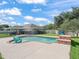 An inviting pool is surrounded by concrete, with two Adirondack chairs and a stone water feature, set in a fenced backyard at 4730 Se 31St St, Ocala, FL 34480