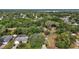 Aerial view of wooded neighborhood with lake in distance. Home has pool and adjacent vacant lot at 501 Cherry Tree St, Eustis, FL 32726