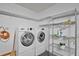 Bright laundry room with full washer and dryer, shelving, and exposed block wall at 501 Cherry Tree St, Eustis, FL 32726