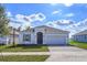 Charming single-story home featuring manicured lawn, neutral color palette, and brick-paved driveway and two-car garage at 5025 Balsam Falls Rd, Deland, FL 32724